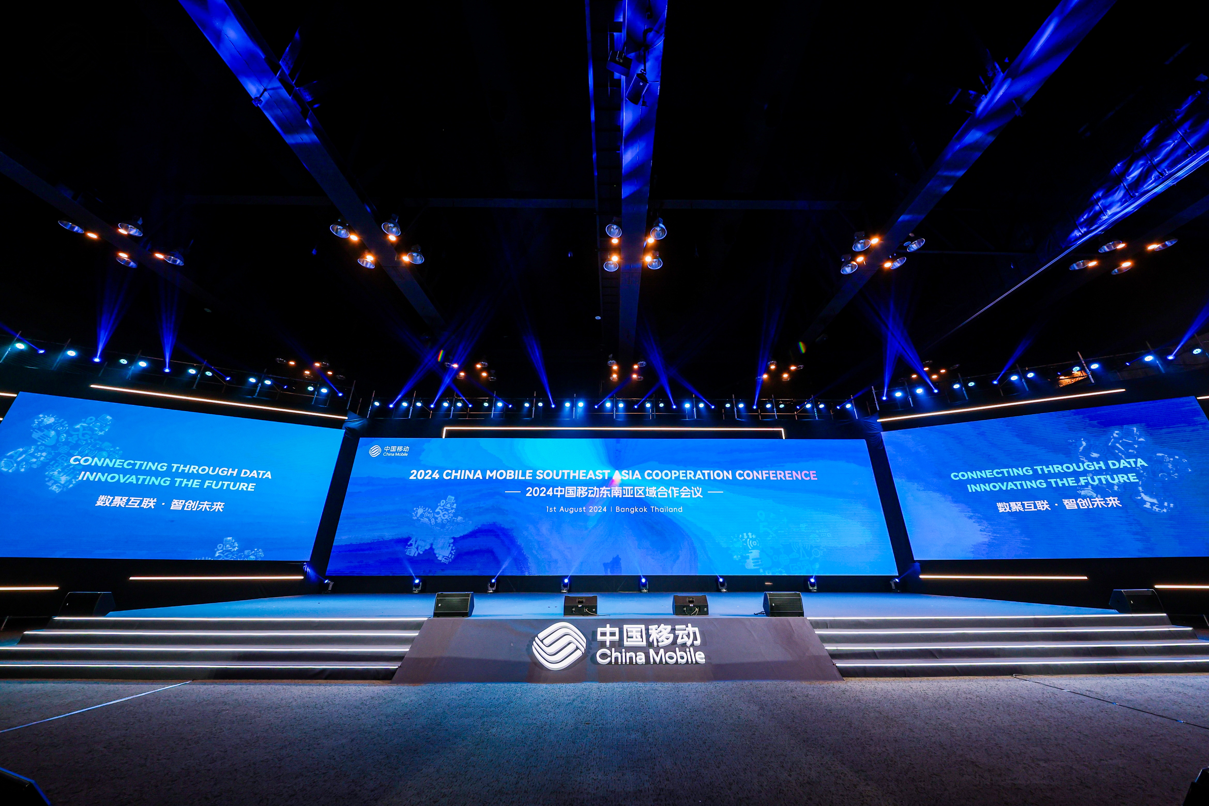 A stage with blue lights and large screens
Description automatically generated